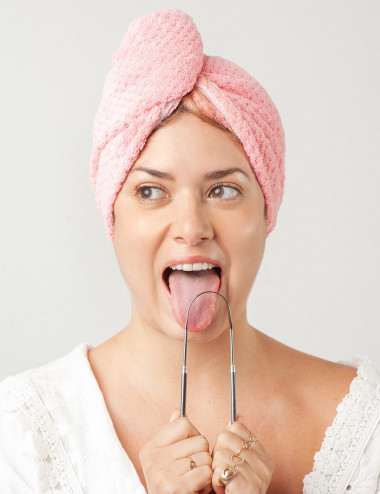 Mujer usando limpiador de lengua de acero inoxidable para higiene bucal